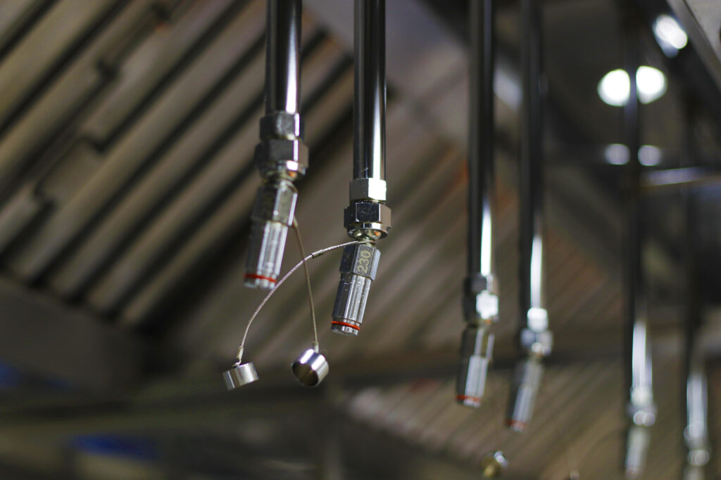 Close view of a commercial kitchen fire suppression installed next to a kitchen hood.